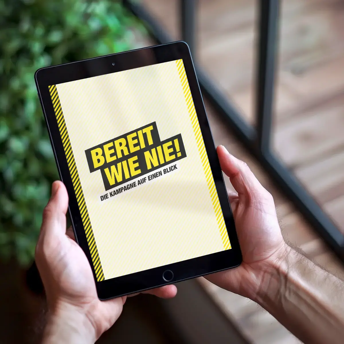 Das Bild zeigt zwei Hände, die ein Tablet halten. Auf dem Tablet kann man den Slogan &quot;BEREIT WIE NIE!&quot; lesen.