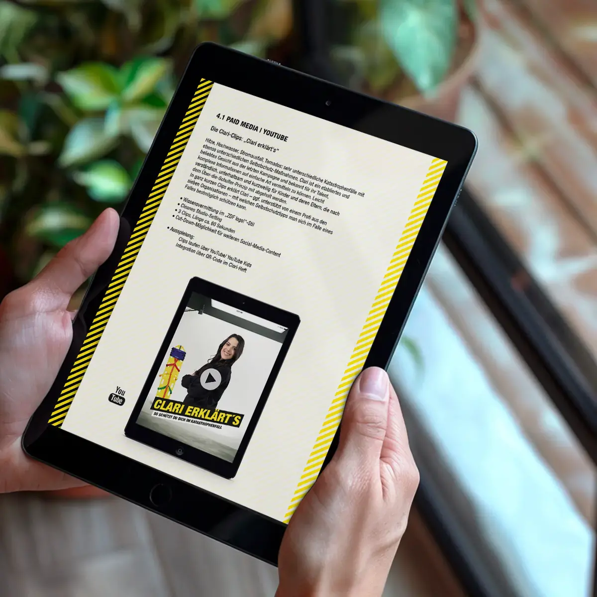 Das Bild zeigt zwei Hände, die ein Tablet halten. Auf dem Tablet ist eine Präsentation mit Kampagneninhalten geöffnet.